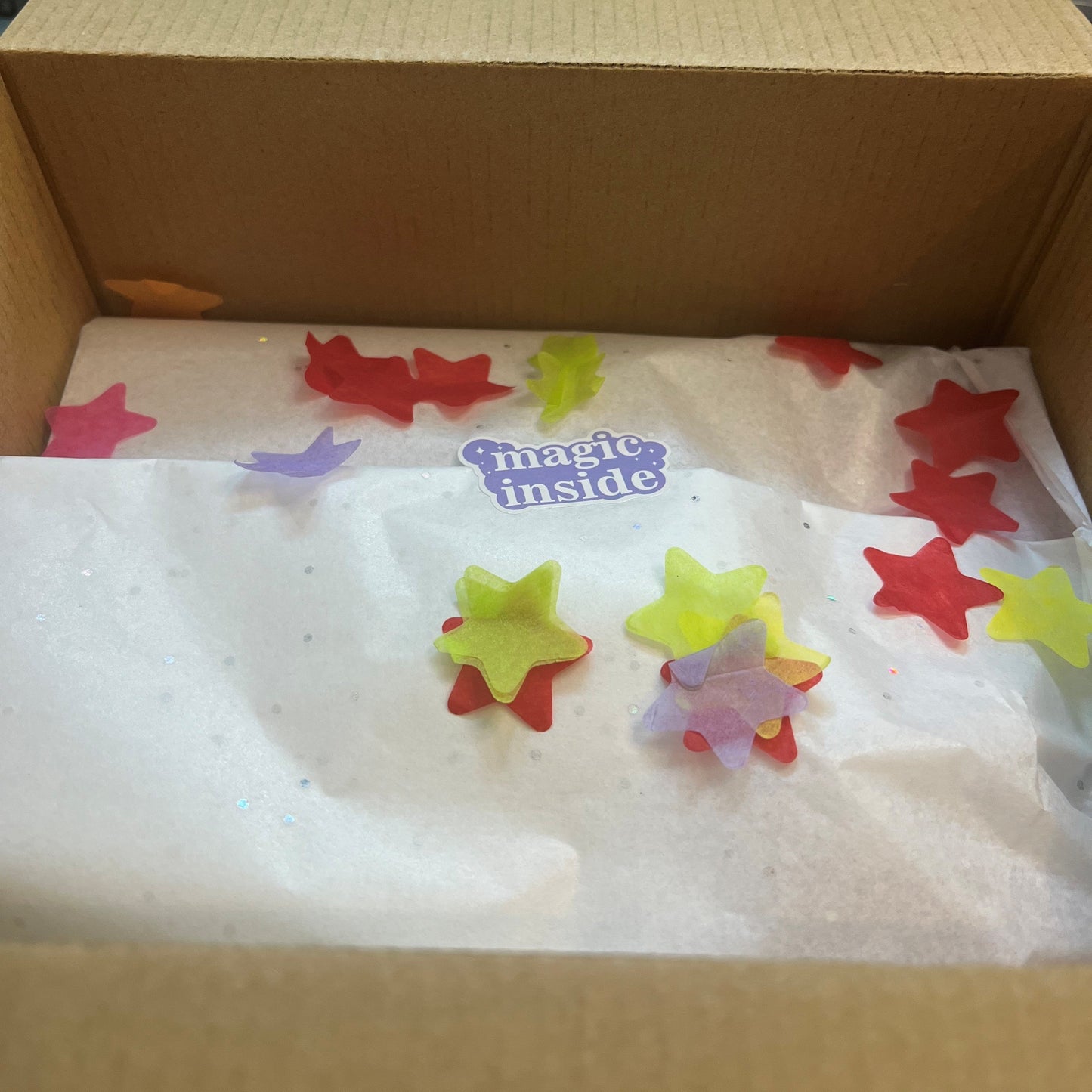 Box with colorful star-shaped objects and a 'magic inside' label on a white background.