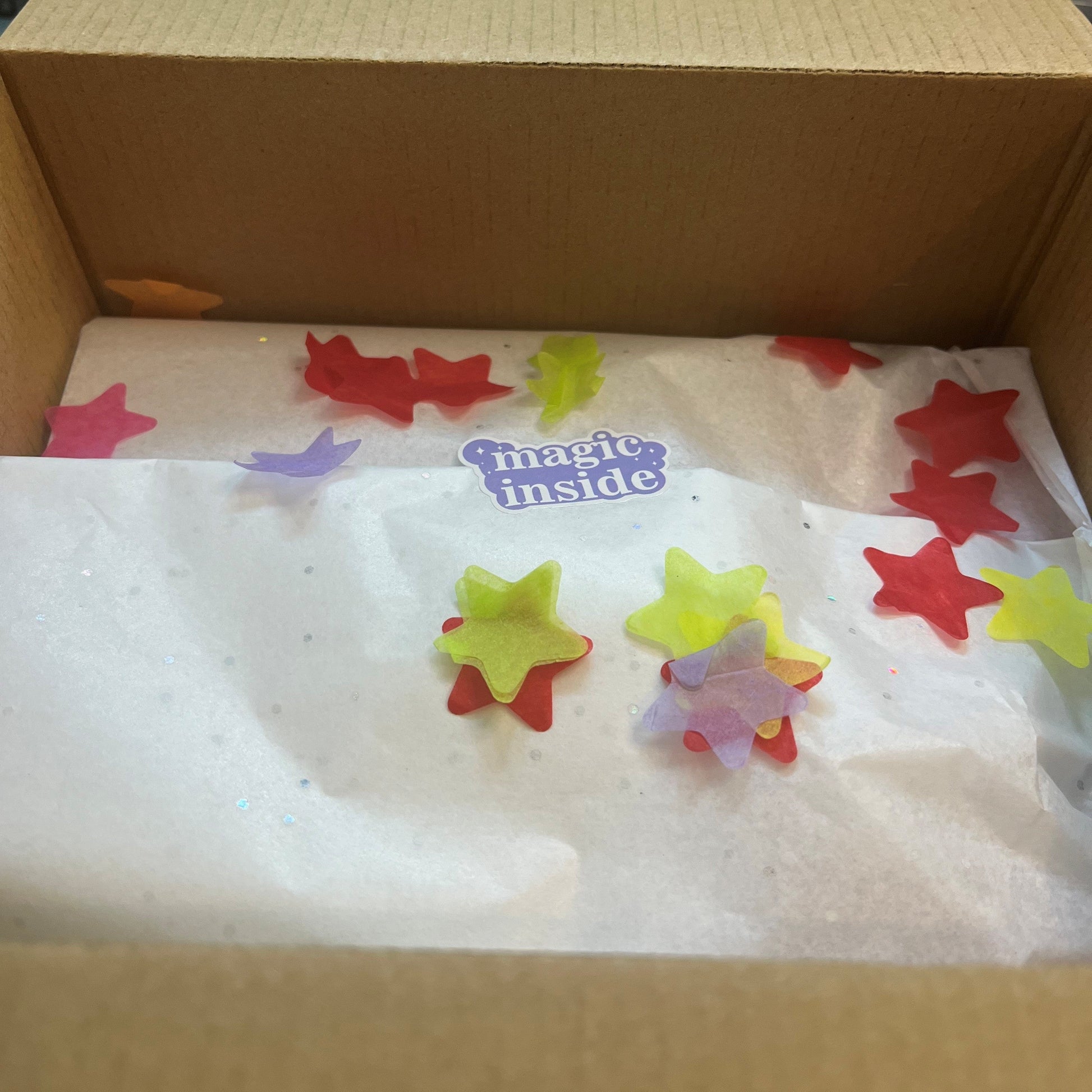 Box with colorful star-shaped objects and a 'magic inside' label on a white background.